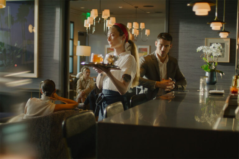 View of The Salon with waitress and guests enjoying the bar as they await for their flights.